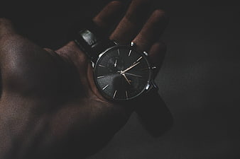 Close-up of a luxury black wristwatch held in a hand