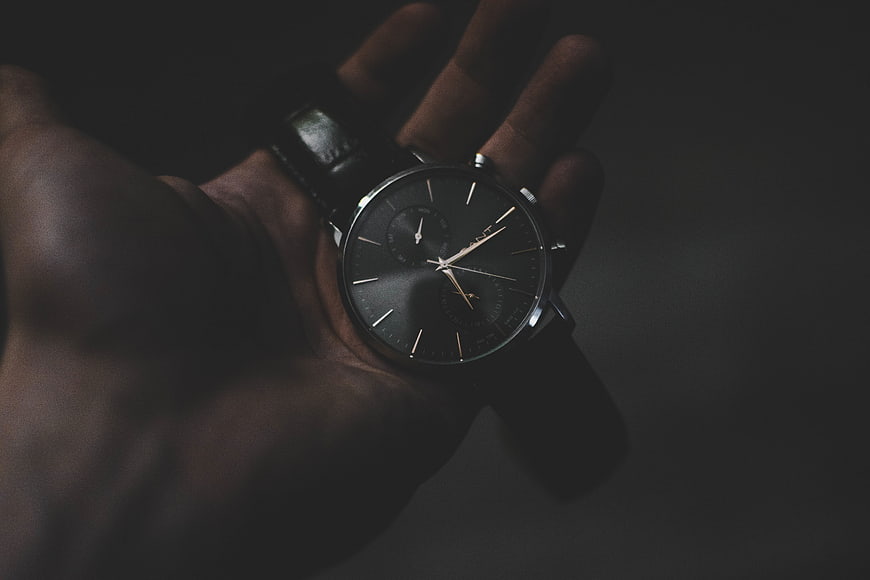 Close-up of a luxury black wristwatch held in a hand