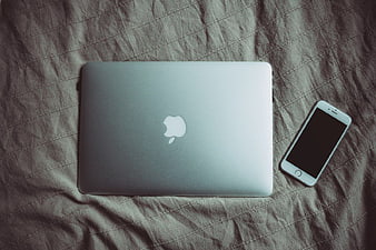 Silver MacBook and iPhone on Textured Bedding