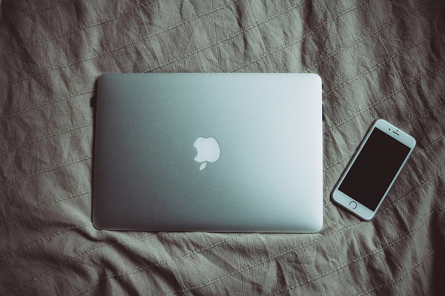 Silver MacBook and iPhone on Textured Bedding