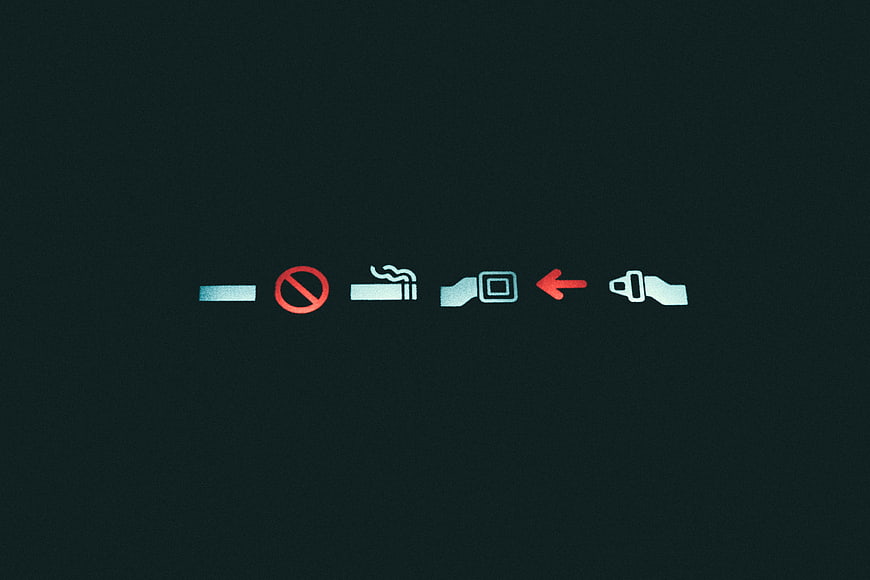 Airplane seatbelt and no smoking signs illuminated in dark cabin