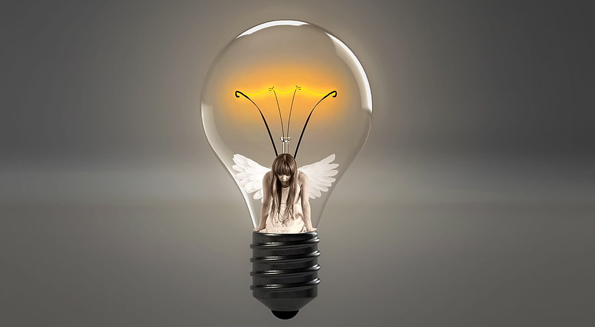Sad fairy with wings resting inside a glowing lightbulb
