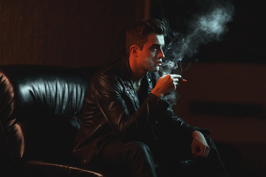 Man in Leather Jacket Smoking Cigarette on Sofa
