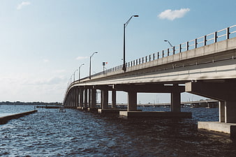 Concrete bridge over water with blue sky and streetlights