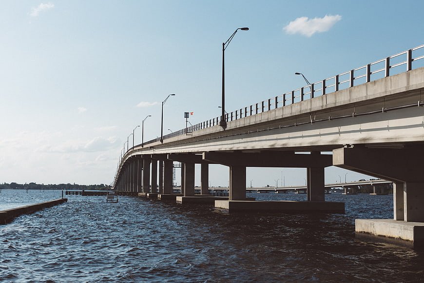 Concrete bridge over water with blue sky and streetlights