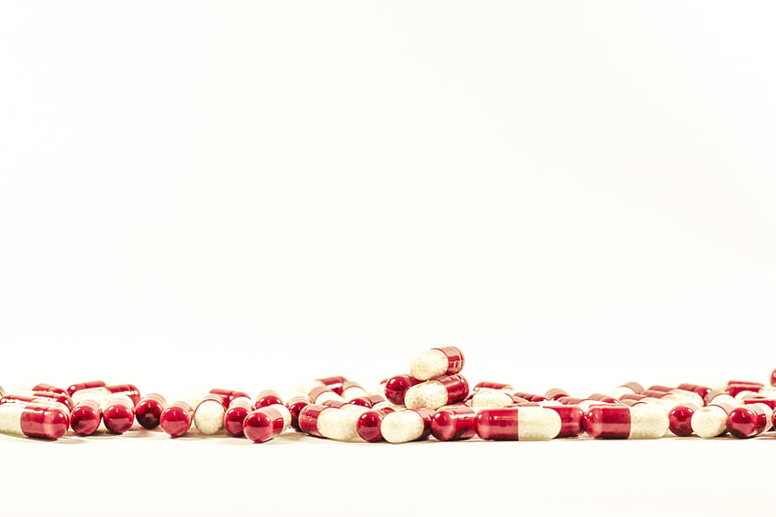 Red and white capsules on white background with copyspace