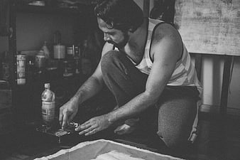 Black and white photo of male artist painting on floor