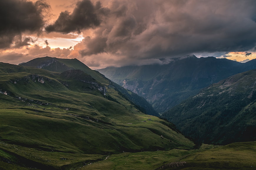 Dramatic sunset over green mountain valley with clouds
