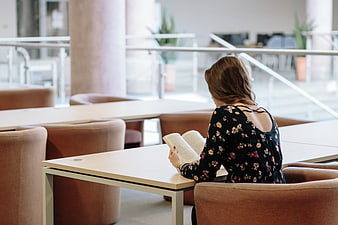 Woman reading book in modern library study area