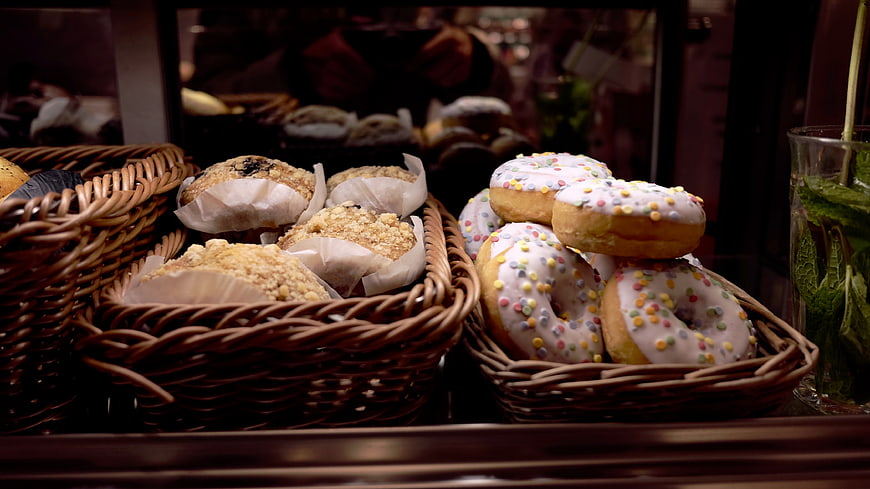 Fresh Donuts and Muffins in Wicker Baskets at Bakery