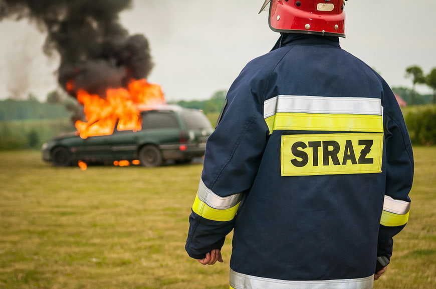 Firefighter Watching Burning Car in Field