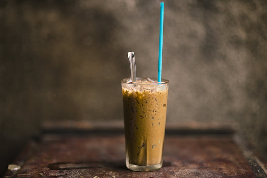 Iced Coffee in Glass with Blue Straw on Rustic Table
