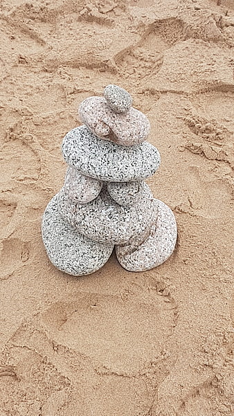 Stacked stones on sandy beach background