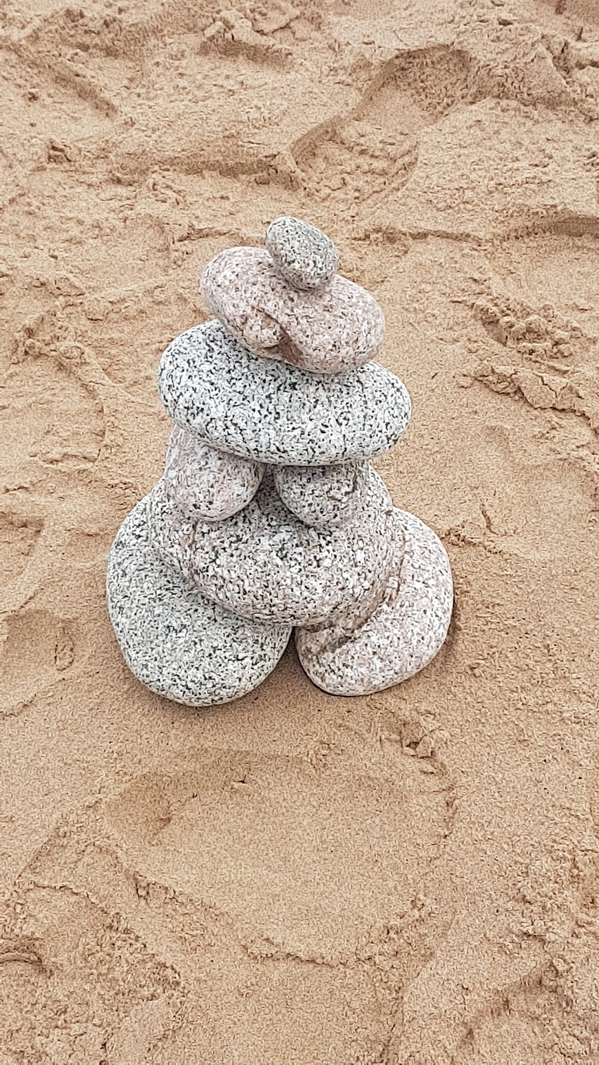 Stacked stones on sandy beach background