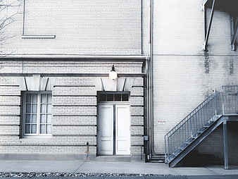 White brick building facade with double doors and metal stairs