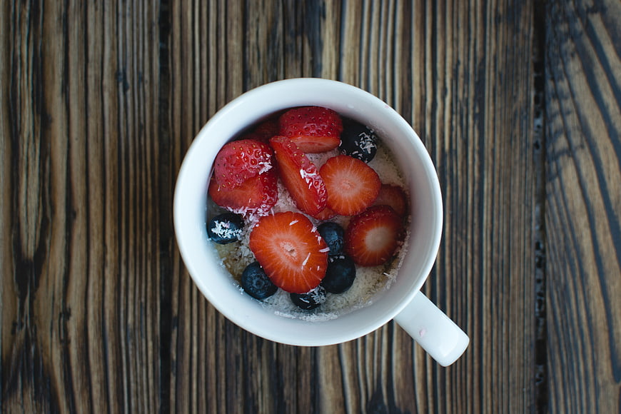 Overhead view of oatmeal cup with strawberries and blueberries
