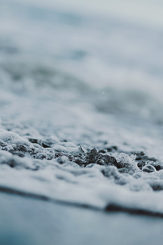 Close-up of frothy ocean waves crashing on a beach