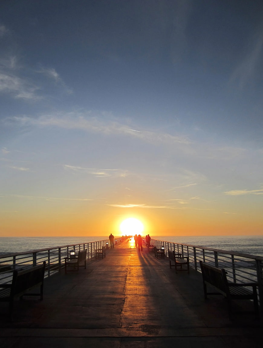 Silhouettes of People Walking on Pier at Sunset