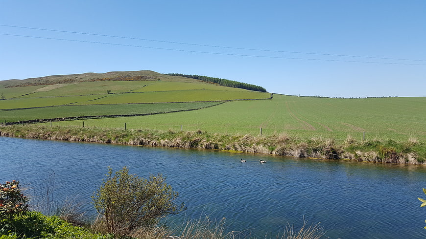Serene River Landscape with Rolling Green Hills and Blue Sky