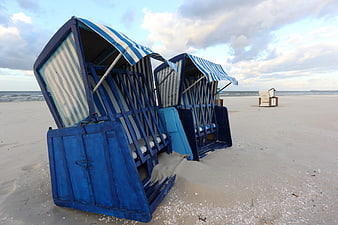 Blue striped beach chairs on sandy shore at dusk