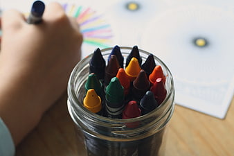 Child Coloring with Crayons in Glass Jar