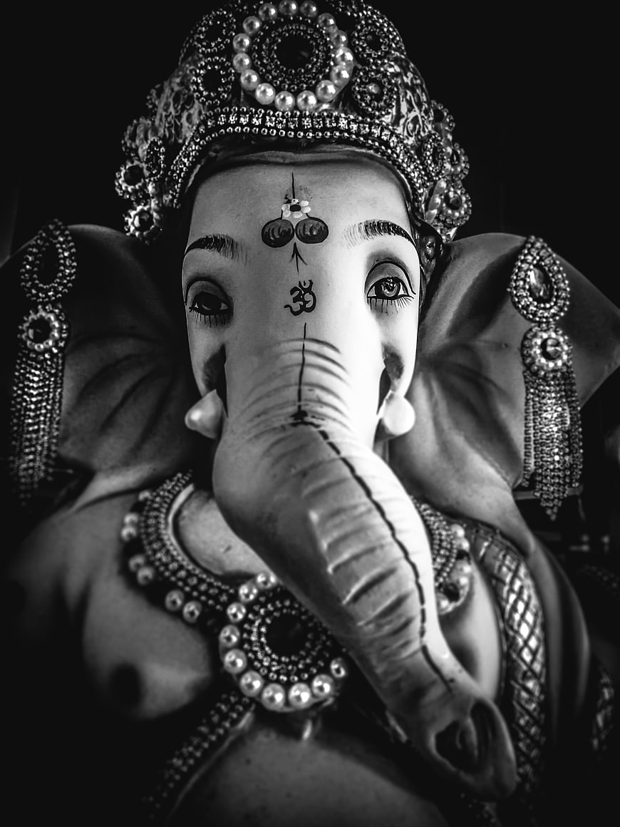 Black and white portrait of ornate Ganesha idol with traditional jewelry