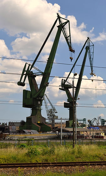 Green industrial cranes at shipyard with railway tracks