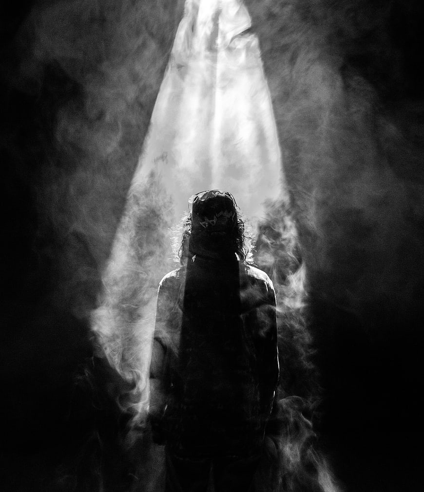 Silhouette of person in smoke with dramatic light beam