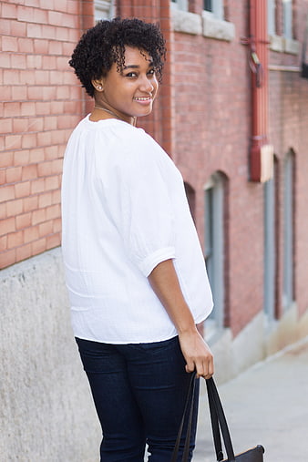 Smiling young woman with curly hair walking outdoors