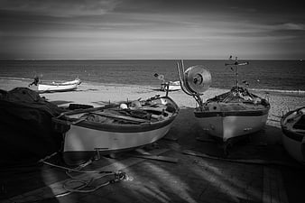 Black and white fishing boats resting on a pebble beach