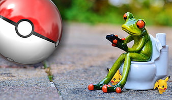Frog figurine on toilet playing smartphone with Pokemon Go theme