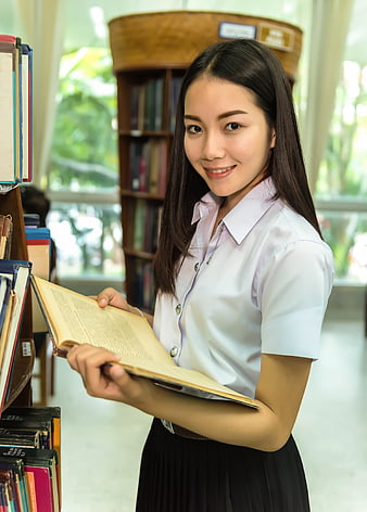 Asian female student reading book in library