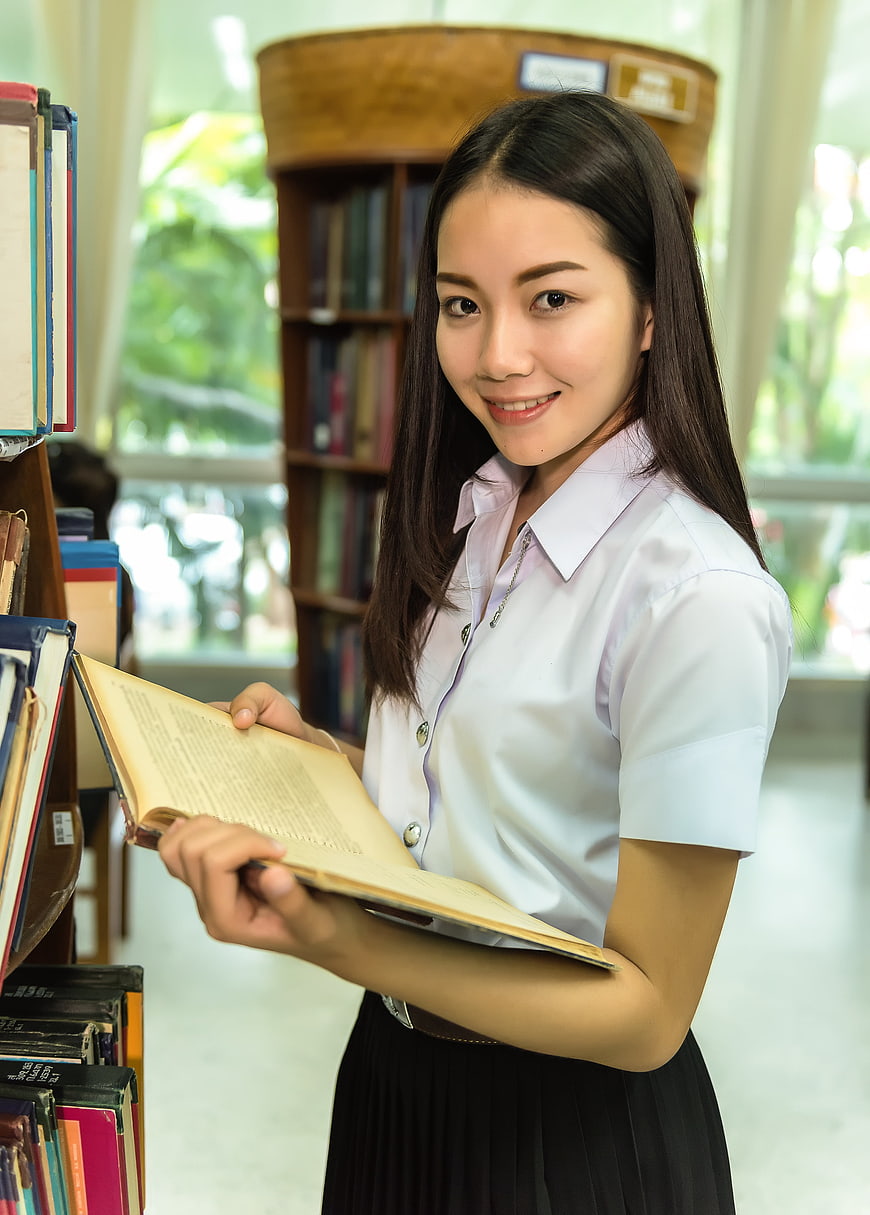 Asian female student reading book in library