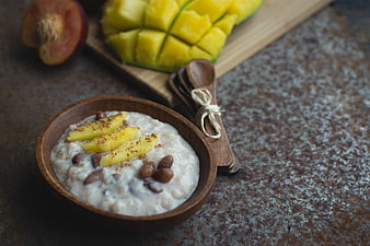 Coconut rice and beans dessert with mango in wooden bowl