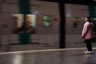 Woman waiting on subway platform with blurred train passing