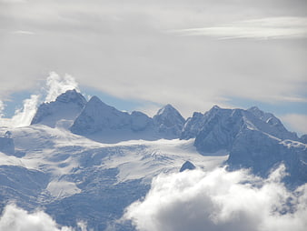 Snowy mountain peaks rising above clouds in winter landscape
