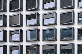 Modern building facade with grid of black windows and blinds