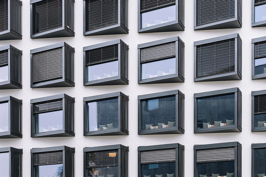 Modern building facade with grid of black windows and blinds