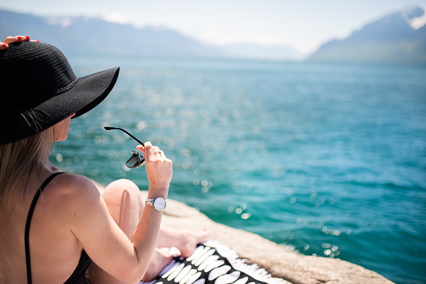 Woman in black hat relaxing by turquoise lake