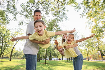 Happy family playing airplane game in park