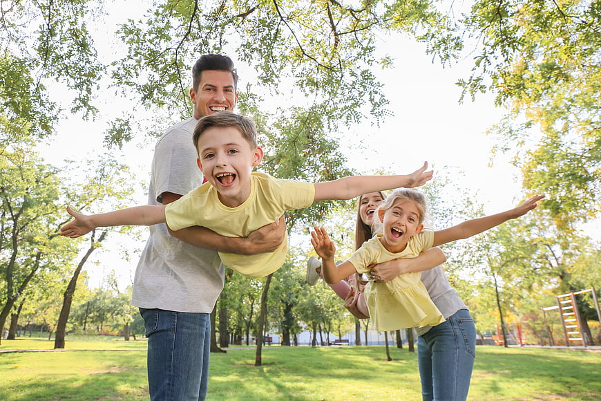 Happy family playing airplane game in park