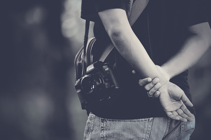 Photographer with DSLR Camera and Hands Behind Back