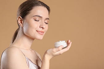 Woman with glowing skin holding white cream jar