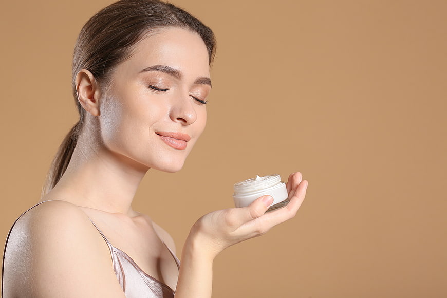 Woman with glowing skin holding white cream jar