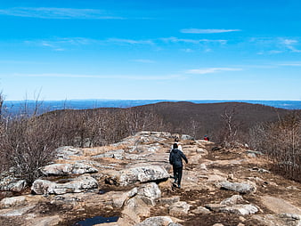 Hikers Walking on Rocky Mountain Ridge Under Blue Sky