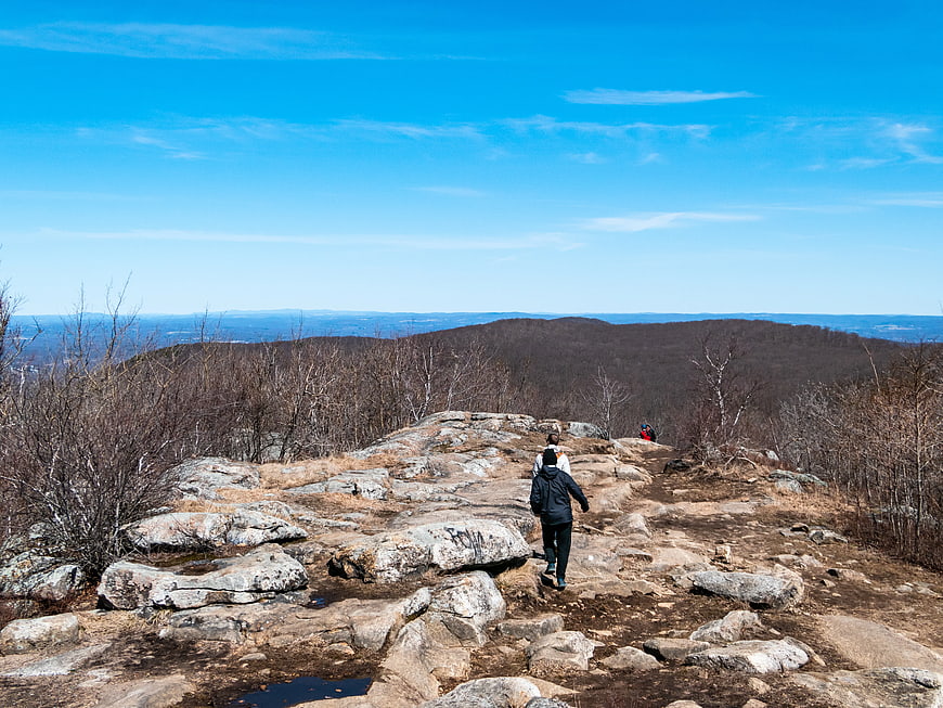 Hikers Walking on Rocky Mountain Ridge Under Blue Sky