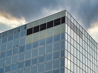 Modern Glass Office Building Corner Against Cloudy Sky