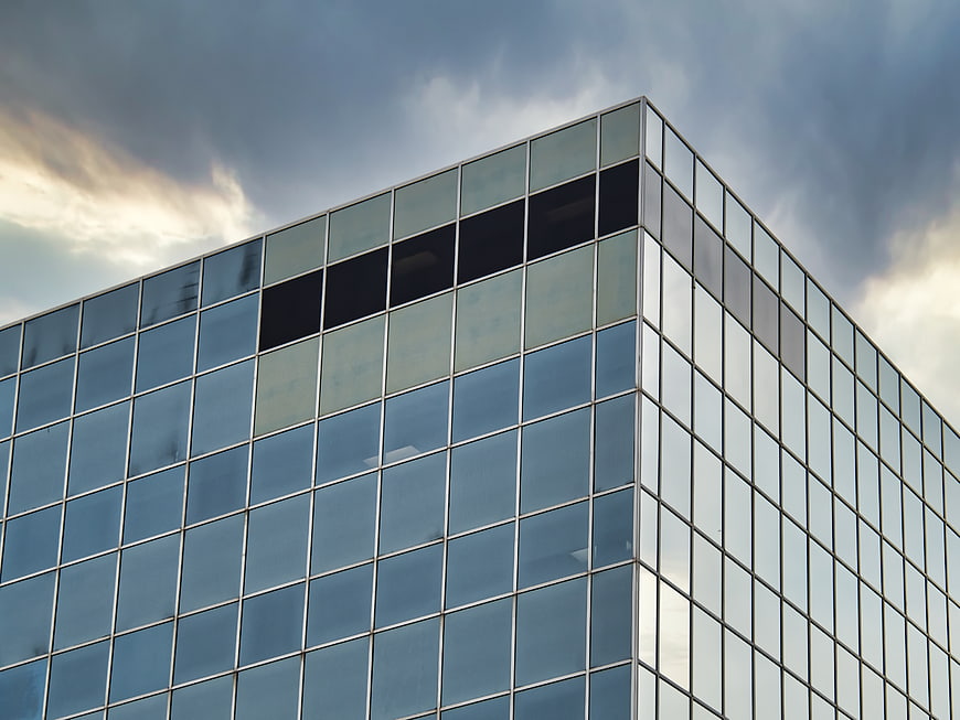 Modern Glass Office Building Corner Against Cloudy Sky