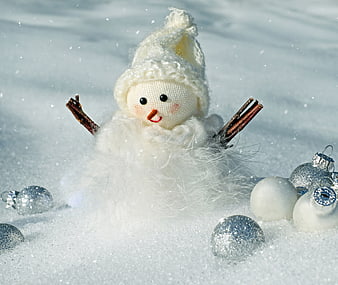 Cute handmade snowman doll with silver ornaments in snow
