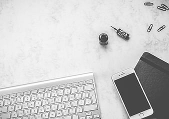 Minimalist black and white office desk flat lay with keyboard and smartphone